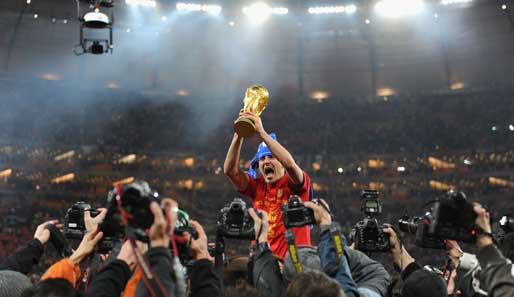 Spaniens Top-Torschütze David Villa inmitten eine Fotografentraube mit Pokal und komischer Kopfbedeckung