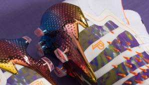 Die "Demonskin"-Gummispikes, die für eine verbesserte Ballkontrolle kalibriert wurden, sind auf dem Schuh in signalorange zu sehen. Zu den Details gehören eine opalisierende Veredelung der Außensohle sowie ein Fersenlogo in Ombre-Regenbogenfarben.