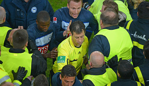 Schiedsrichter Wolfang Stark (M.), umringt von Security und wütenden Hertha-Spielern.