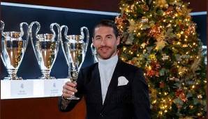Real Madrids Verteidiger Sergio Ramos posiert mit einem Gläschen Sekt vor dem Weihnachtsbaum - und seinen etlichen Champions-League-Pokalen.