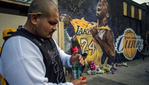 Ein Fan zündet eine Kerze für den Verstorbenen an, im Hintergrund ist das Kobe-Bryant-Mural in Downtown Los Angeles zu sehen.